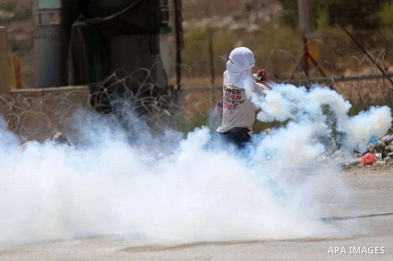 A Palestinian protester throws back a tear gas canister fired by Israeli troops during clashes following a protest in solidarity with Palestinian prisoners held in Israeli jails, near Israel's Ofer Prison near the West B...