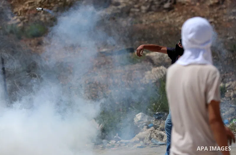 A Palestinian protester throws back a tear gas canister fired by Israeli troops during clashes following a protest in solidarity with Palestinian prisoners held in Israeli jails, near Israel's Ofer Prison near the West B...