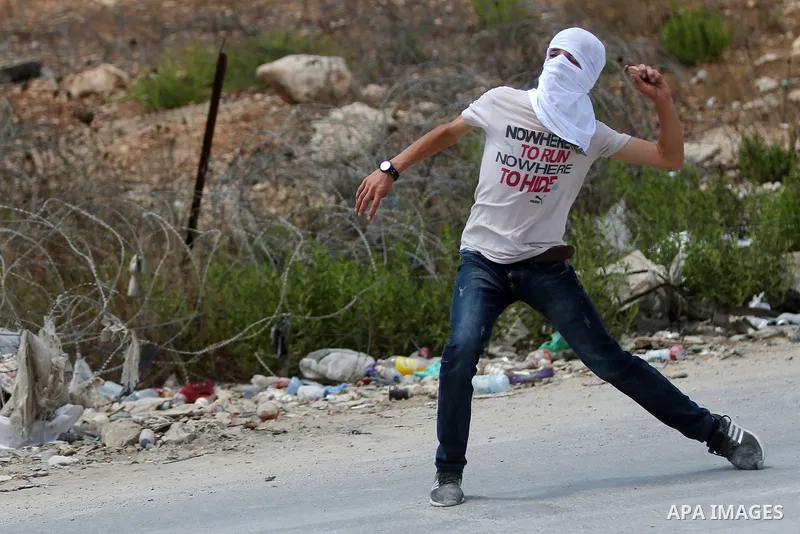 A Palestinian protester throws back a tear gas canister fired by Israeli troops during clashes following a protest in solidarity with Palestinian prisoners held in Israeli jails, near Israel's Ofer Prison near the West B...