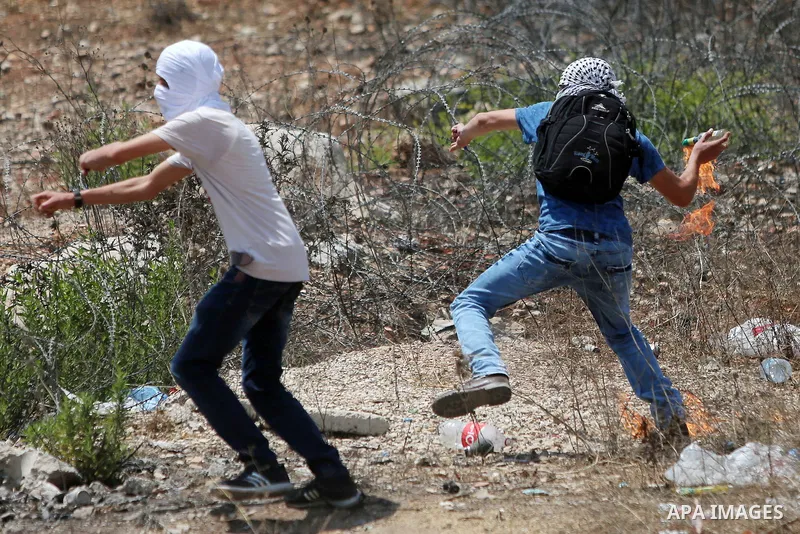 A Palestinian protester prepares to throw a molotov cocktail towards Israeli troops during clashes following a protest in solidarity with Palestinian prisoners held in Israeli jails, near Israel's Ofer Prison near the We...