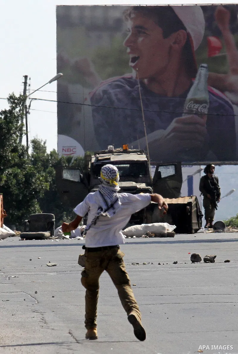 A Palestinian protester hurls stones towards Israeli troops during clashes following a protest in solidarity with Palestinian prisoners held in Israeli jails, at the Hawara checkpoint near the West Bank city of Nablus on...