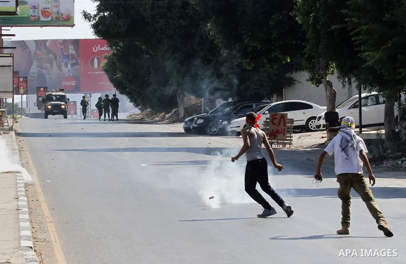 A Palestinian protester kicks a tear gas canister fired by Israeli troops during clashes following a protest in solidarity with Palestinian prisoners held in Israeli jails, at the Hawara checkpoint near the West Bank cit...