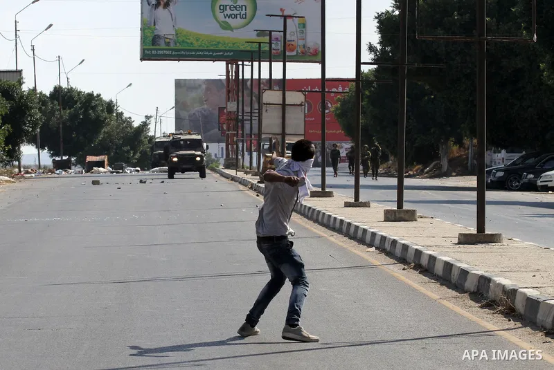 A Palestinian protester hurls stones towards Israeli troops during clashes following a protest in solidarity with Palestinian prisoners held in Israeli jails, at the Hawara checkpoint near the West Bank city of Nablus on...