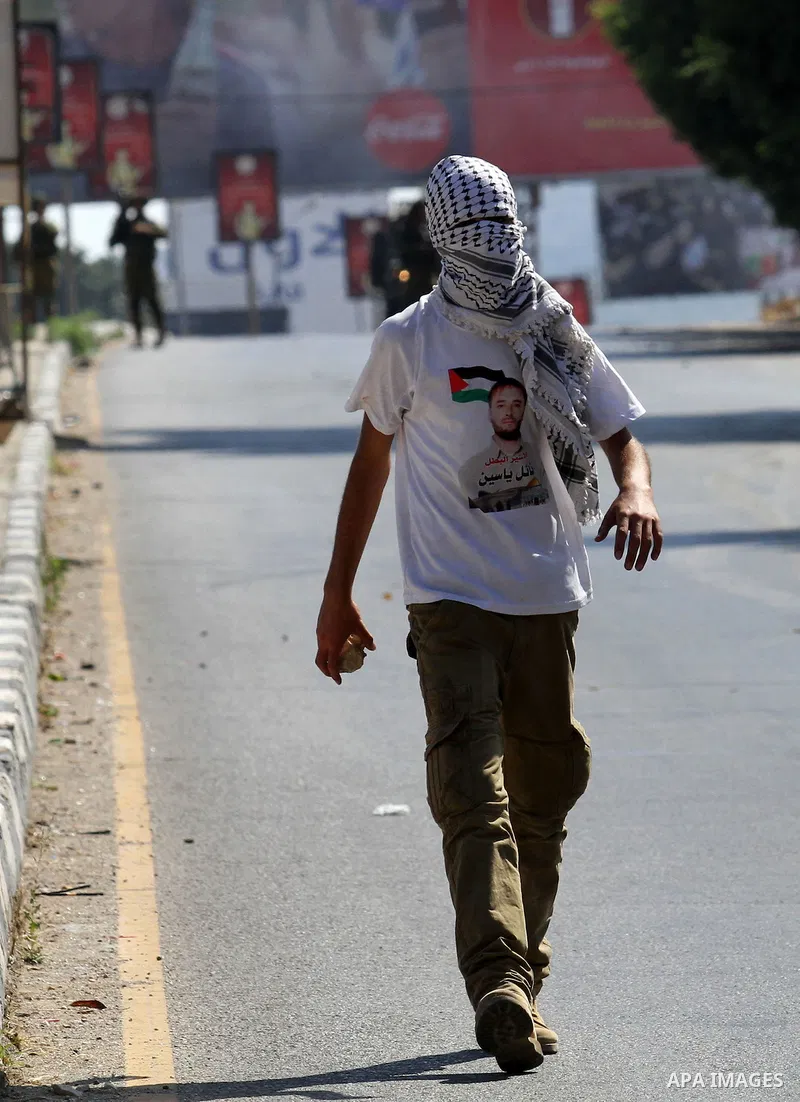 A Palestinian protester carries stones towards Israeli troops during clashes following a protest in solidarity with Palestinian prisoners held in Israeli jails, at the Hawara checkpoint near the West Bank city of Nablus...