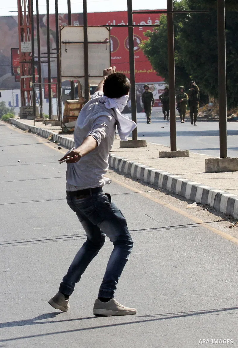 A Palestinian protester hurls stones towards Israeli troops during clashes following a protest in solidarity with Palestinian prisoners held in Israeli jails, at the Hawara checkpoint near the West Bank city of Nablus on...