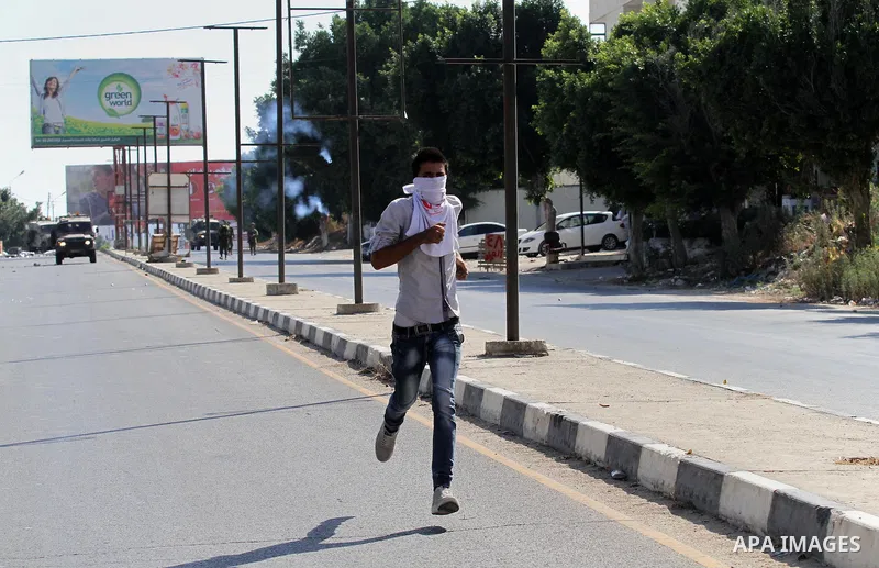 A Palestinian protester runs during clashes with Israeli troops following a protest in solidarity with Palestinian prisoners held in Israeli jails, at the Hawara checkpoint near the West Bank city of Nablus on Aug. 18, 2...