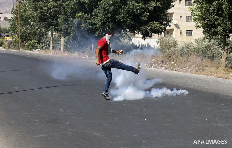 A Palestinian protester kicks a tear gas canister fired by Israeli troops during clashes following a protest in solidarity with Palestinian prisoners held in Israeli jails, at the Hawara checkpoint near the West Bank cit...