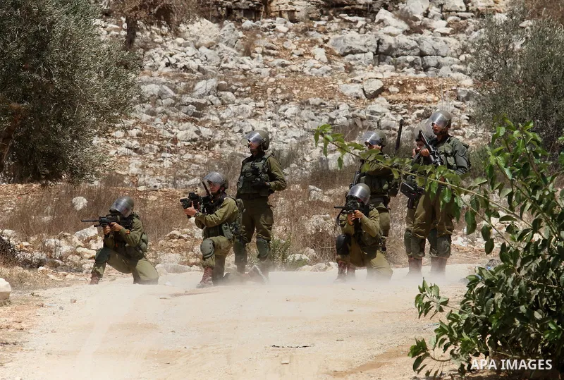 An Israeli soldier aims his weapon at Palestinian protesters during clashes following a weekly demonstration against the expropriation of Palestinian land by Israel on August 19, 2016, in the village of Kfar Qaddum, near...