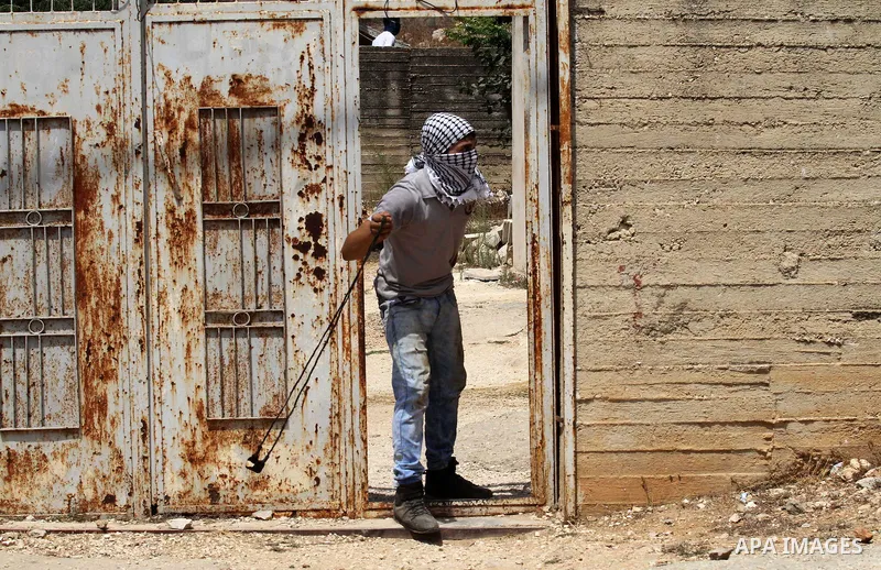 A Palestinian protester uses a slingshot to hurl stones towards Israeli security forces during clashes following a weekly demonstration against the expropriation of Palestinian land by Israel on August 19, 2016, in the v...