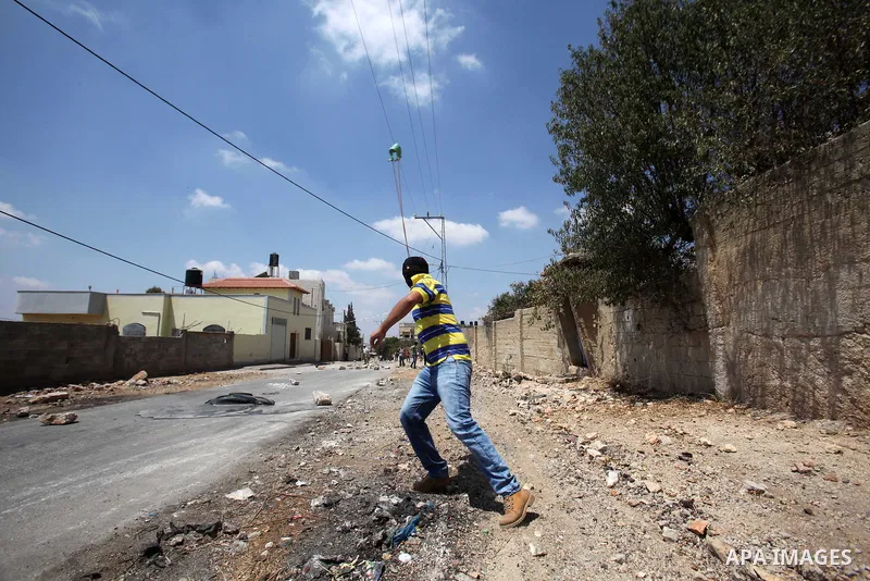 A Palestinian protester uses a slingshot to hurl stones towards Israeli security forces during clashes following a weekly demonstration against the expropriation of Palestinian land by Israel on August 19, 2016, in the v...