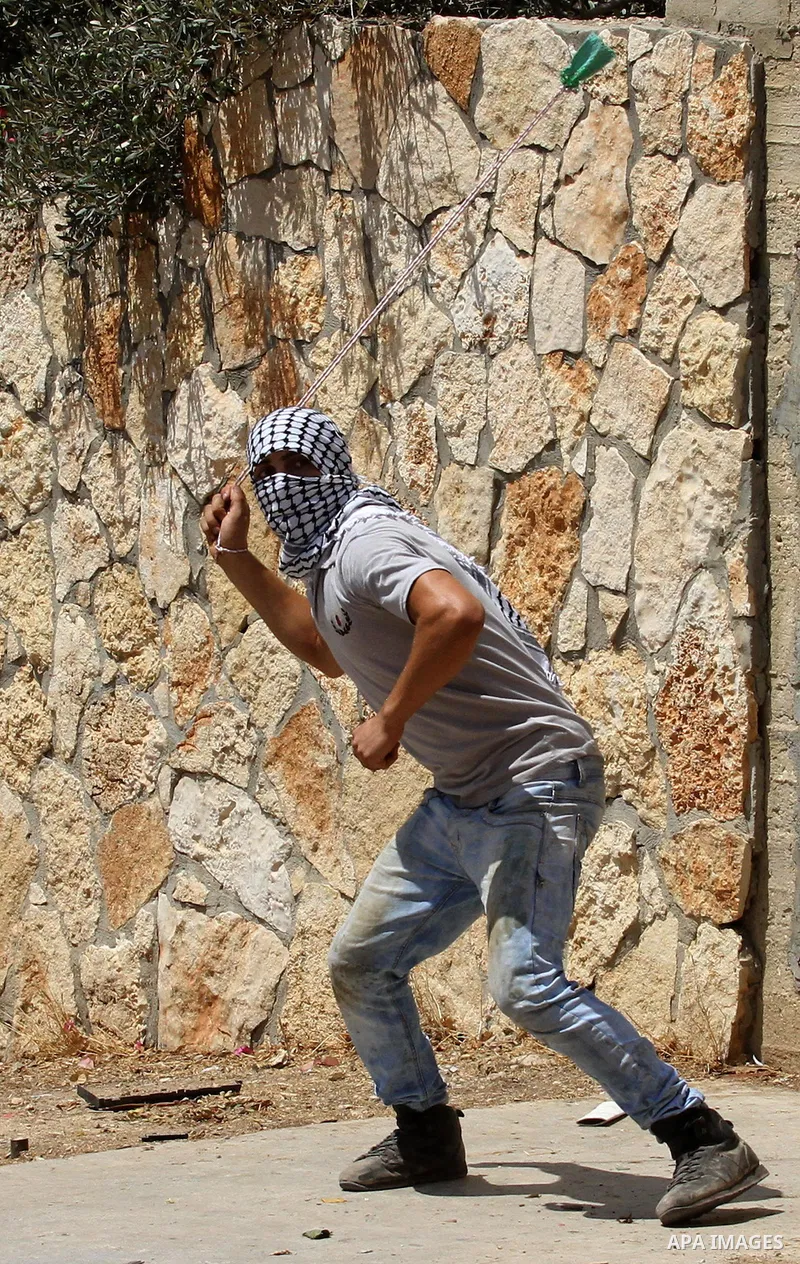 A Palestinian protester uses a slingshot to hurl stones towards Israeli security forces during clashes following a weekly demonstration against the expropriation of Palestinian land by Israel on August 19, 2016, in the v...