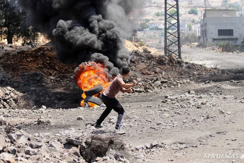 A Palestinian protester uses a slingshot to hurl stones towards Israeli security forces during clashes following a weekly demonstration against the expropriation of Palestinian land by Israel on August 19, 2016, in the v...