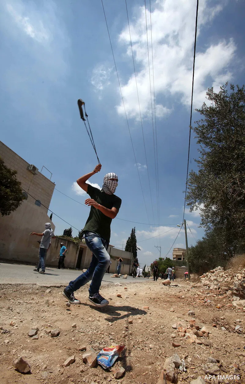 A Palestinian protester uses a slingshot to hurl stones towards Israeli security forces during clashes following a weekly demonstration against the expropriation of Palestinian land by Israel on August 19, 2016, in the v...