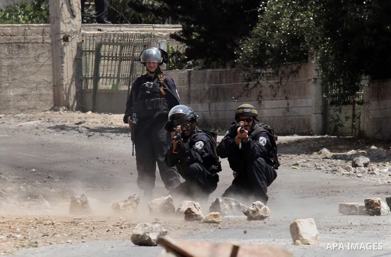 An Israeli soldier aims his weapon at Palestinian protesters during clashes following a weekly demonstration against the expropriation of Palestinian land by Israel on August 19, 2016, in the village of Kfar Qaddum, near...