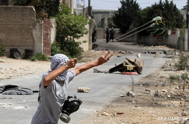 A Palestinian protester uses a slingshot to hurl stones towards Israeli security forces during clashes following a weekly demonstration against the expropriation of Palestinian land by Israel on August 19, 2016, in the v...