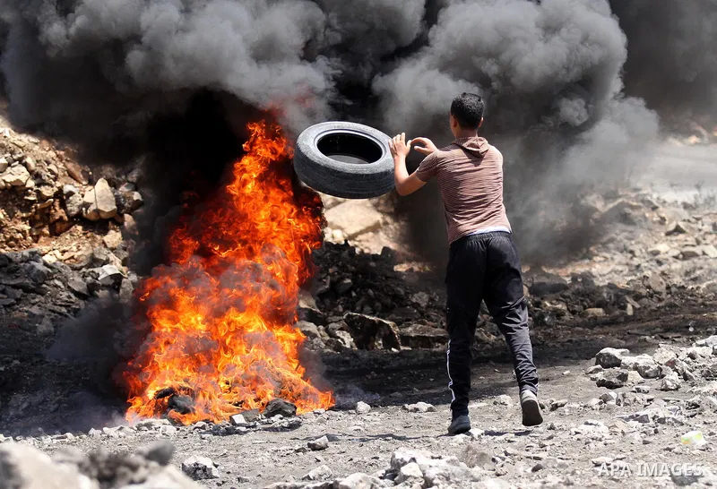 A Palestinian protester burns tires during clashes with Israeli security forces following a weekly demonstration against the expropriation of Palestinian land by Israel on August 19, 2016, in the village of Kfar Qaddum,...