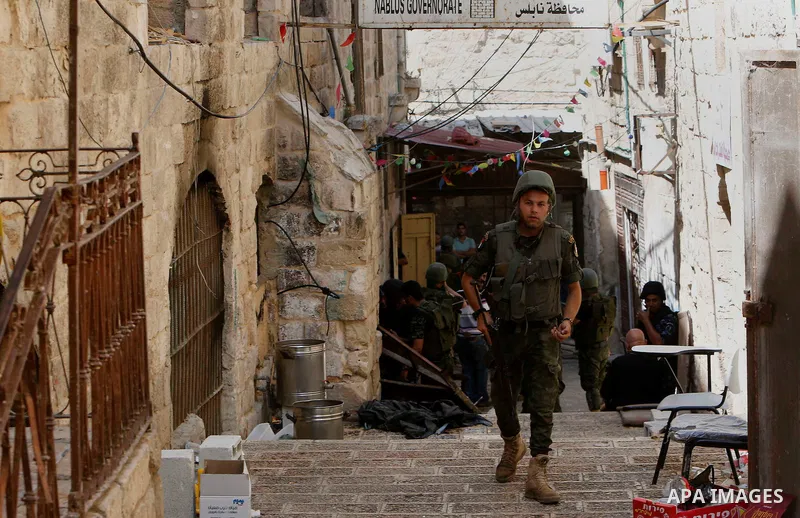 Members of Palestinian security forces take position during a raid following clashes with Palestinian gunmen in the old town of the West Bank city of Nablus, August 19, 2016. Photo by Nedal Eshtayah