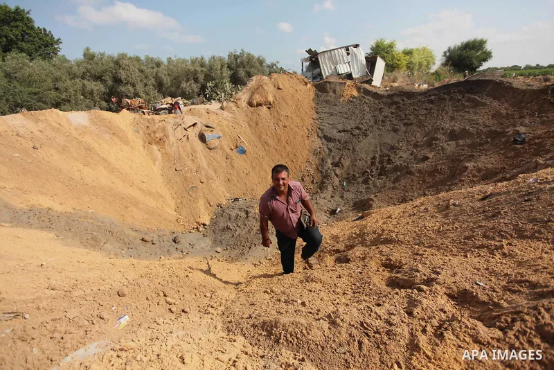 Palestinian security men arrive to inspect a crater on August 22, 2016 in Beit Lahia in the northern Gaza Strip, following an Israeli airstrike the day before that targeted Hamas positions in the Gaza Strip in response t...