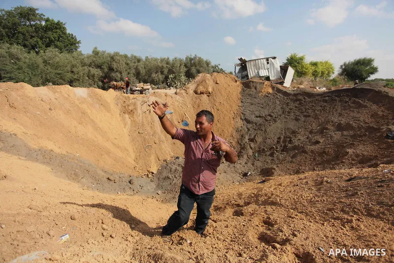 Palestinian security men arrive to inspect a crater on August 22, 2016 in Beit Lahia in the northern Gaza Strip, following an Israeli airstrike the day before that targeted Hamas positions in the Gaza Strip in response t...