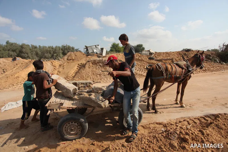 Palestinian men load stones on a cart next to a crater on August 22, 2016 in Beit Lahia in the northern Gaza Strip, following an Israeli airstrike the day before that targeted Hamas positions in the Gaza Strip in respons...