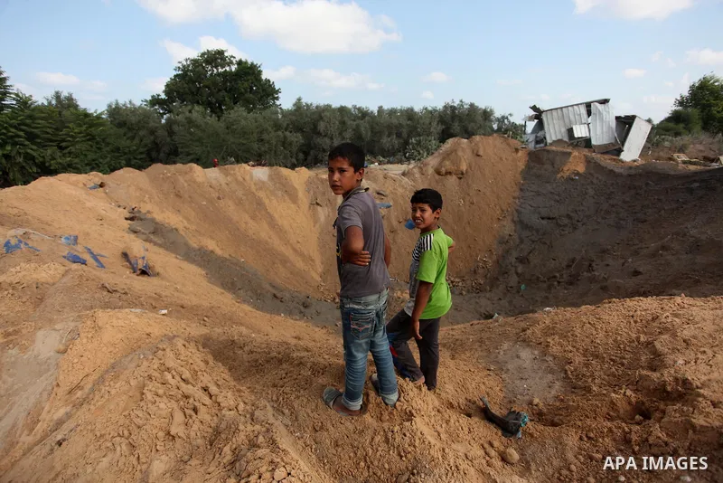 Palestinian children stand next to a crater on August 22, 2016 in Beit Lahia in the northern Gaza Strip, following an Israeli airstrike the day before that targeted Hamas positions in the Gaza Strip in response to a rock...