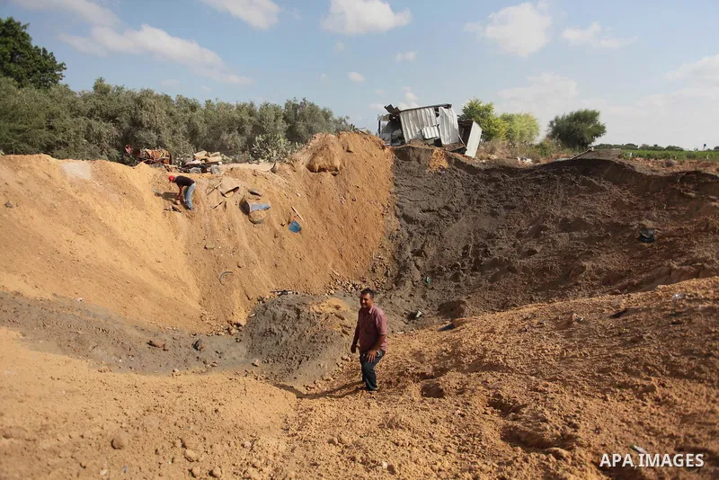 Palestinian security men arrive to inspect a crater on August 22, 2016 in Beit Lahia in the northern Gaza Strip, following an Israeli airstrike the day before that targeted Hamas positions in the Gaza Strip in response t...