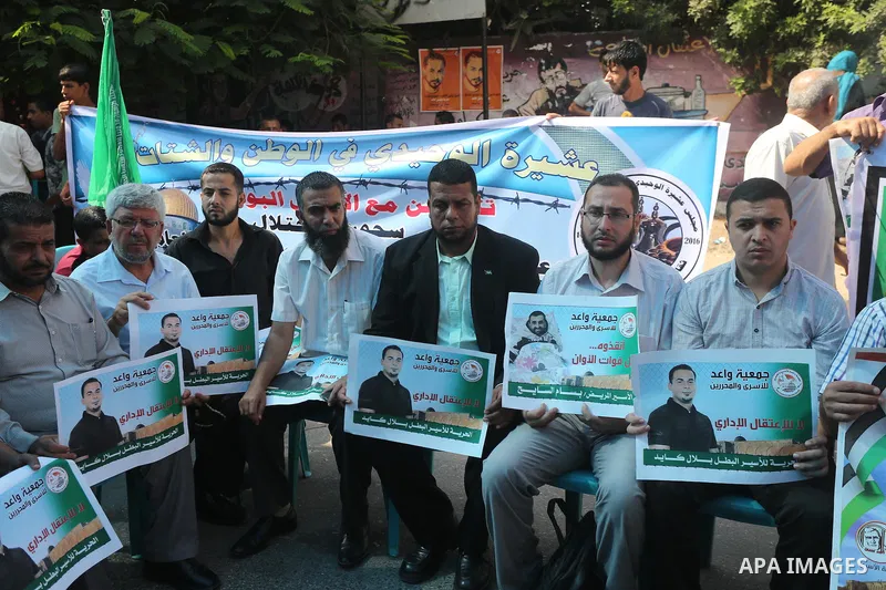 Palestinians hold posters against administrative detention and in support of Palestinian prisoner Bilal Kayed (portrait), who has been fasting for almost two months over his detention without trial, in front of Red Cross...