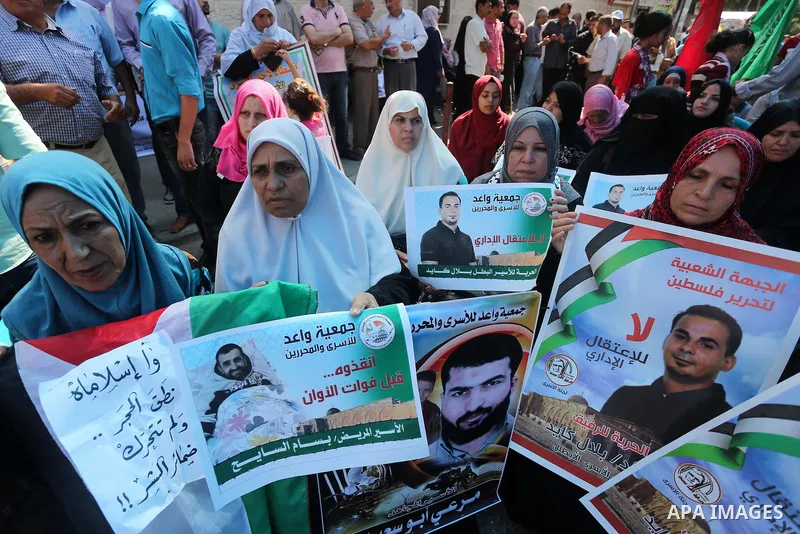 Palestinians hold posters against administrative detention and in support of Palestinian prisoner Bilal Kayed (portrait), who has been fasting for almost two months over his detention without trial, in front of Red Cross...