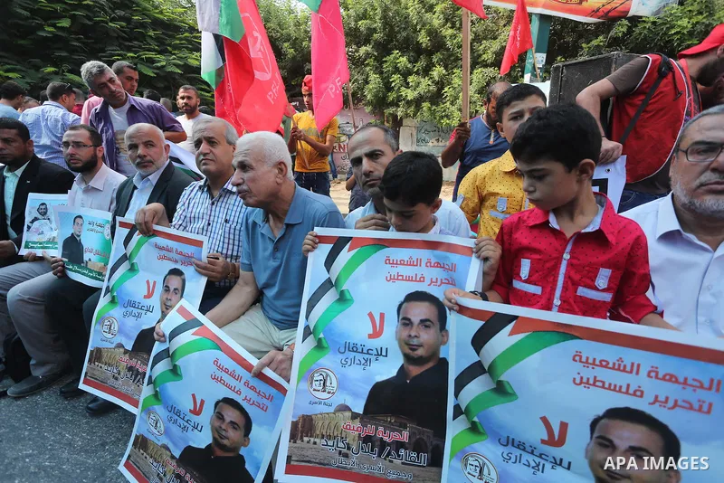 Palestinians hold posters against administrative detention and in support of Palestinian prisoner Bilal Kayed (portrait), who has been fasting for almost two months over his detention without trial, in front of Red Cross...