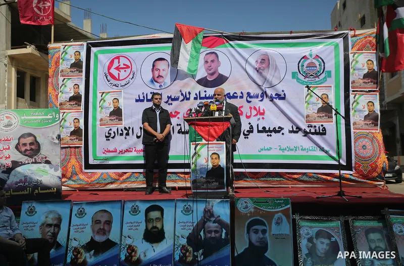 Palestinians hold posters against administrative detention and in support of Palestinian prisoner Bilal Kayed (portrait), who has been fasting for almost two months over his detention without trial, in front of Red Cross...