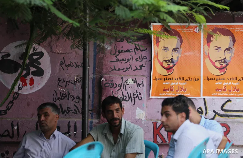 Palestinians hold posters against administrative detention and in support of Palestinian prisoner Bilal Kayed (portrait), who has been fasting for almost two months over his detention without trial, in front of Red Cross...