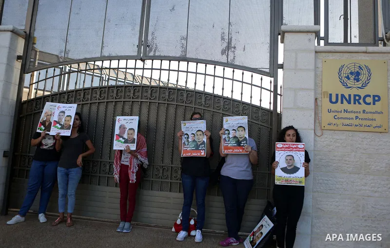 Palestinians hold posters against administrative detention and in support of Palestinian prisoner Bilal Kayed, who has been fasting for almost two months over his detention without trial, outside the United Nations Ramal...
