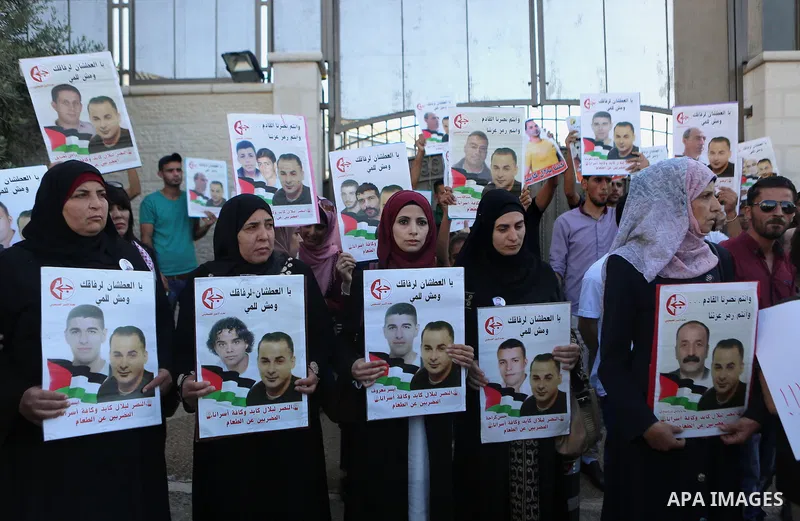Palestinians hold posters against administrative detention and in support of Palestinian prisoner Bilal Kayed, who has been fasting for almost two months over his detention without trial, outside the United Nations Ramal...