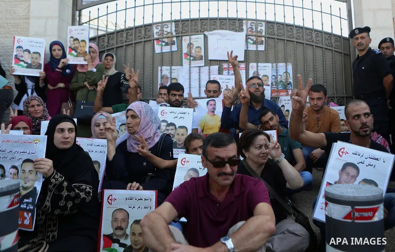 Palestinians hold posters against administrative detention and in support of Palestinian prisoner Bilal Kayed, who has been fasting for almost two months over his detention without trial, outside the United Nations Ramal...