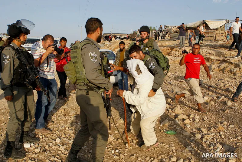 Israeli border policemen carry away a Palestinian man after Israeli troops demolished his house near the West Bank village of Um AlKhair, south of Hebron August 24, 2016. Photo by Wisam Hashlamoun