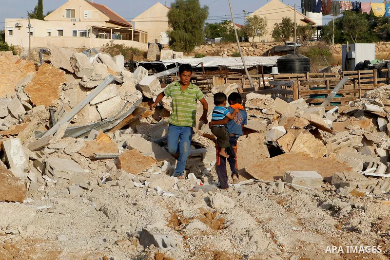 Palestinian children stand on the rubble after Israeli troops demolished their house near the West Bank village of Um AlKhair, south of Hebron August 24, 2016. Photo by Wisam Hashlamoun