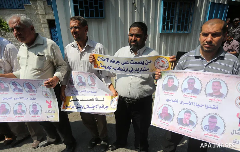 Palestinian protesters hold posters of Bilal Kayed, who stage hunger strike in Israeli jails, in front of the high commissioner for human rights headquarters in Gaza City, on Aug. 24, 2016. Photo by Mohammed Asad