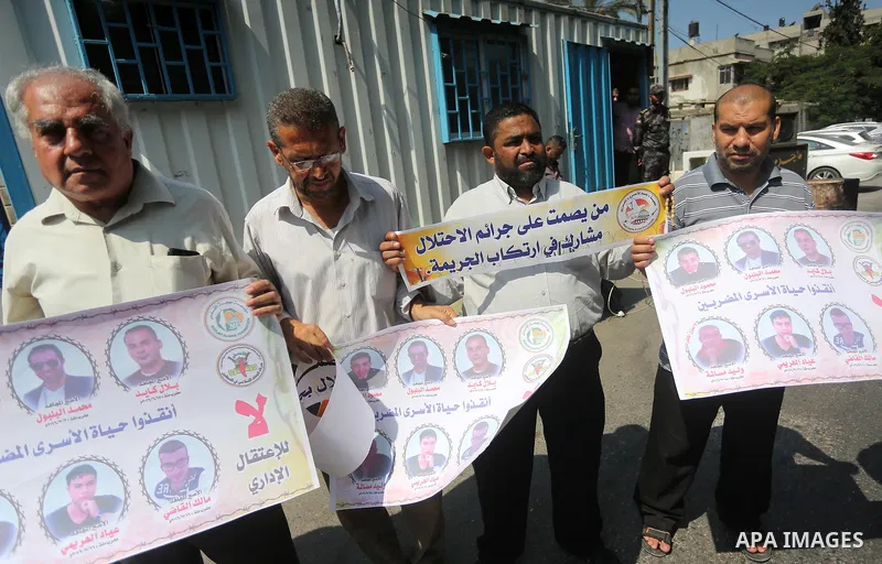 Palestinian protesters hold posters of Bilal Kayed, who stage hunger strike in Israeli jails, in front of the high commissioner for human rights headquarters in Gaza City, on Aug. 24, 2016. Photo by Mohammed Asad