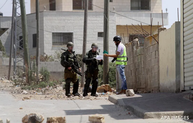Israeli security forces check Palestinian photographer identity during clashes with Palestinian protesters following a weekly demonstration against the expropriation of Palestinian land by Israel on August 26, 2016, in t...