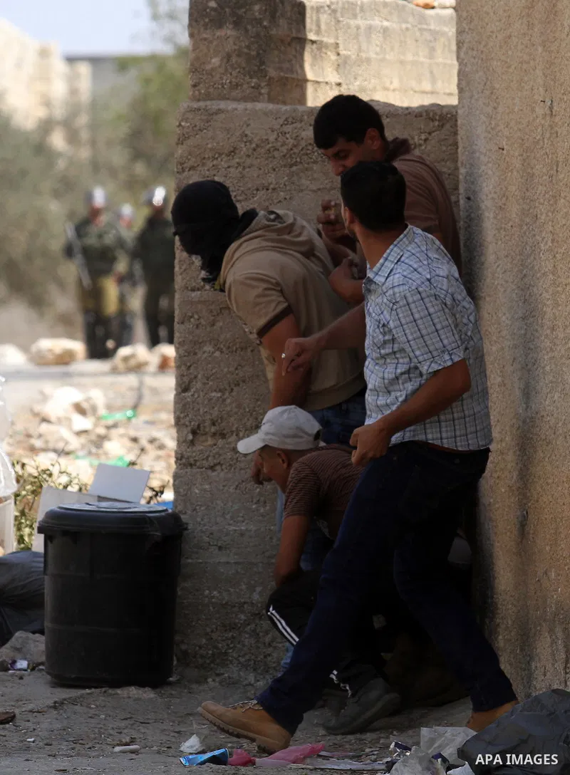 Palestinian protesters take cover during clashes with Israeli security forces following a weekly demonstration against the expropriation of Palestinian land by Israel on August 26, 2016, in the village of Kfar Qaddum, ne...