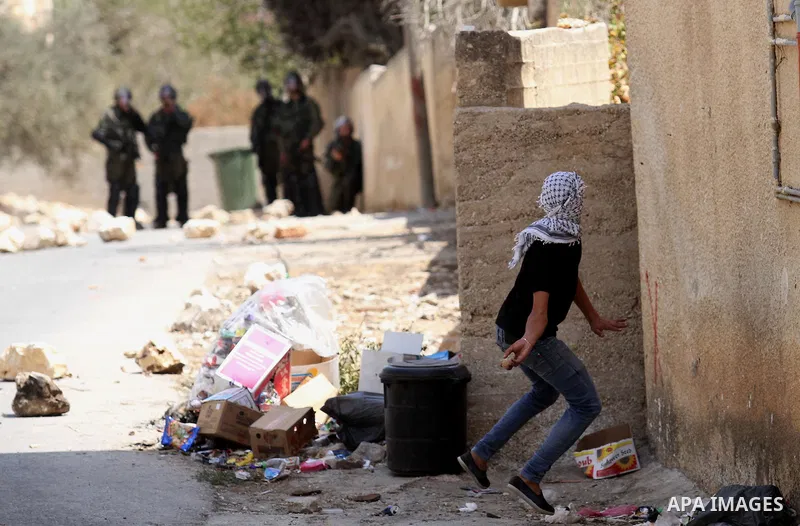 A Palestinian protester hurls stones towards Israeli security forces during clashes following a weekly demonstration against the expropriation of Palestinian land by Israel on August 26, 2016, in the village of Kfar Qadd...
