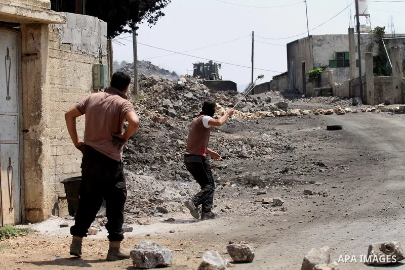 A Palestinian protester uses a slingshot to hurl stones towards Israeli security forces during clashes following a weekly demonstration against the expropriation of Palestinian land by Israel on August 26, 2016, in the v...