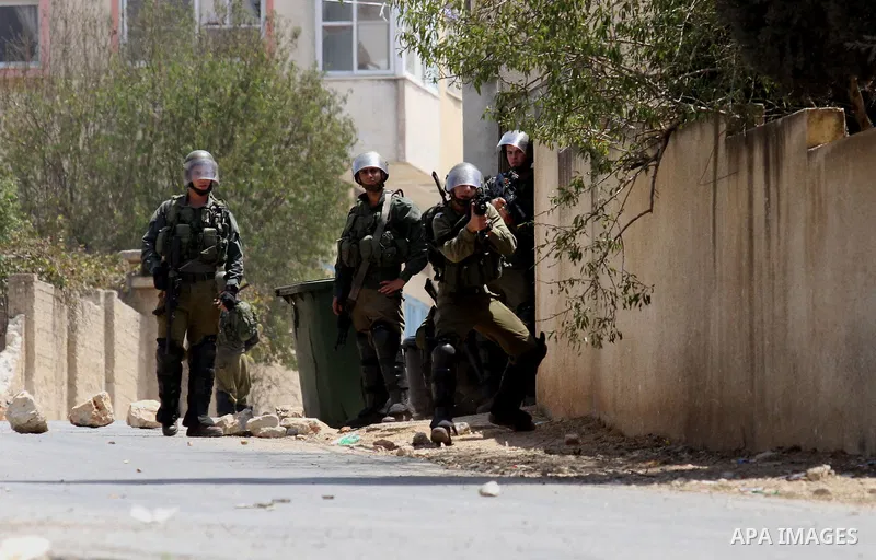 An Israeli soldier aims his weapon at Palestinian protesters during clashes following a weekly demonstration against the expropriation of Palestinian land by Israel on August 26, 2016, in the village of Kfar Qaddum, near...