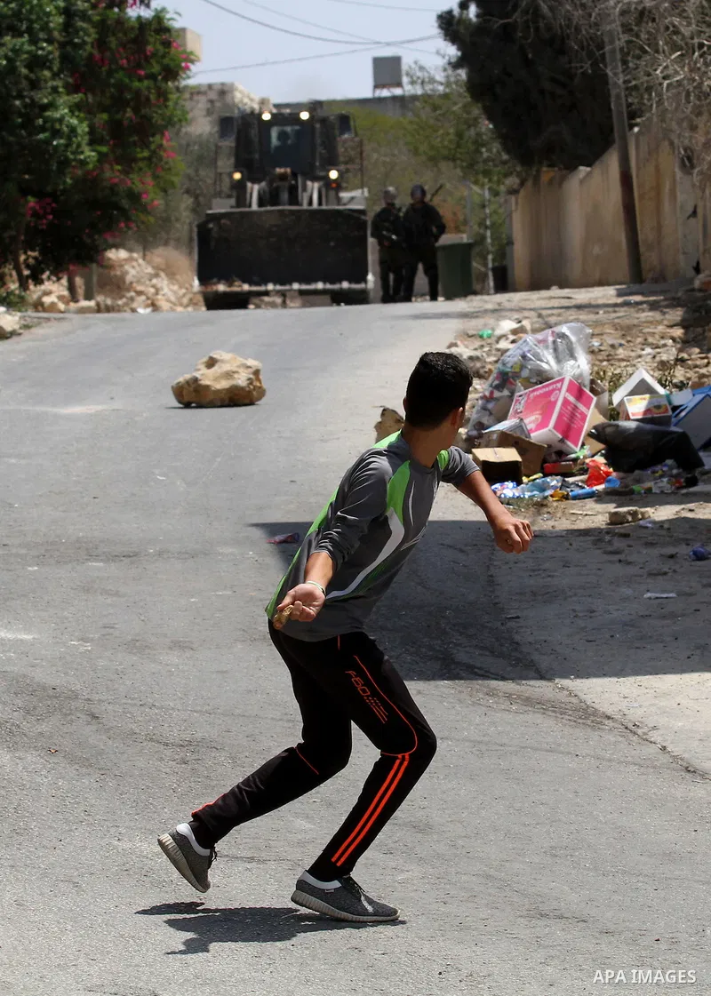 A Palestinian protester hurls stones towards Israeli security forces during clashes following a weekly demonstration against the expropriation of Palestinian land by Israel on August 26, 2016, in the village of Kfar Qadd...