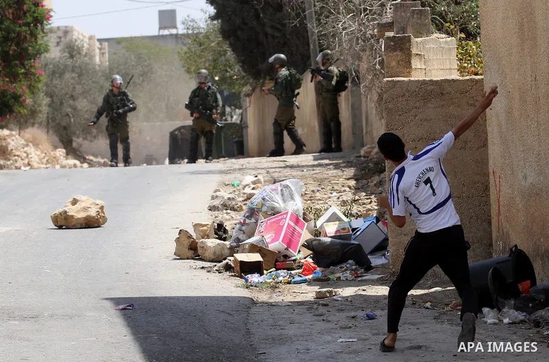 A Palestinian protester hurls stones towards Israeli security forces during clashes following a weekly demonstration against the expropriation of Palestinian land by Israel on August 26, 2016, in the village of Kfar Qadd...
