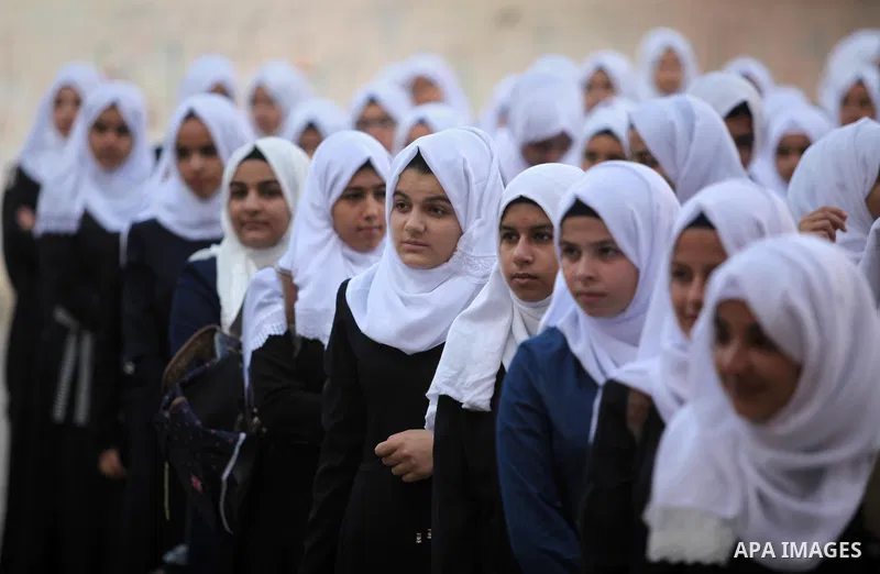 Palestinian schoolgirls play exercises inside their school in the morning of the first day of the new year study in Khan Younis in the southern Gaza Strip August 28, 2016. The mural reads. Photo by Ashraf Amra