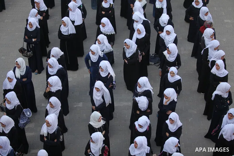 Palestinian schoolgirls play exercises inside their school in the morning of the first day of the new year study in Khan Younis in the southern Gaza Strip August 28, 2016. The mural reads. Photo by Ashraf Amra