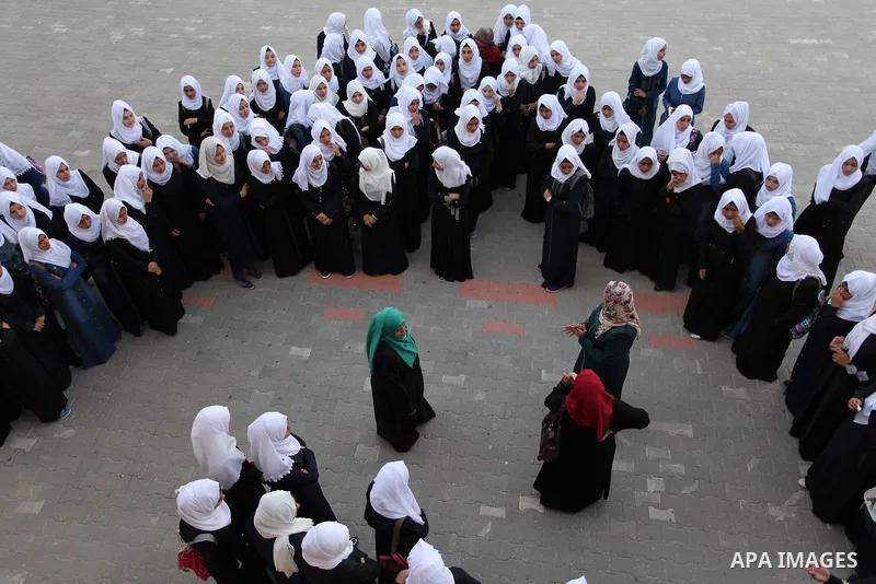 Palestinian schoolgirls play exercises inside their school in the morning of the first day of the new year study in Khan Younis in the southern Gaza Strip August 28, 2016. The mural reads. Photo by Ashraf Amra