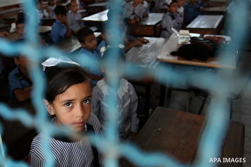 A Palestinian girl looks out of a classroom window as she attends a lesson on the first day of a new school year, at a United Nations-run school in Khan Younis in the southern Gaza Strip August 28, 2016. Photo by Ashraf...