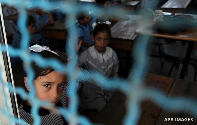 A Palestinian girl looks out of a classroom window as she attends a lesson on the first day of a new school year, at a United Nations-run school in Khan Younis in the southern Gaza Strip August 28, 2016. Photo by Ashraf...